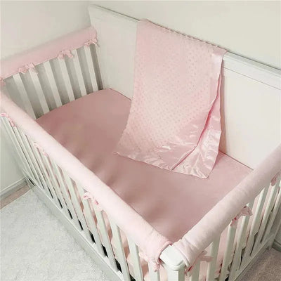Heavenly soft pink chenille minky dot receiving blanket draped over a white crib with pink bedding.