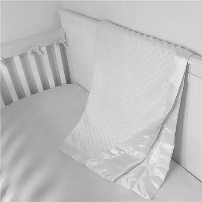 Heavenly Soft Chenille Minky Dot Receiving Blanket in white draped over a crib mattress.