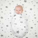 Smiling baby swaddled in a white knit blanket with a star pattern, resting on a matching crib sheet.