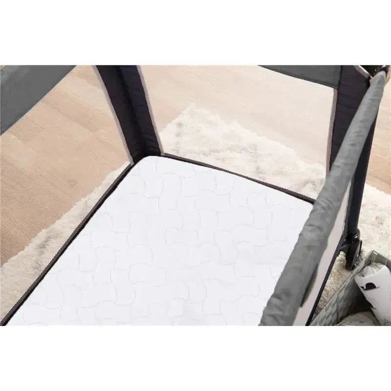 Waterproof Pack N Play mattress protector displayed inside a playard, featuring a quilted white surface.
