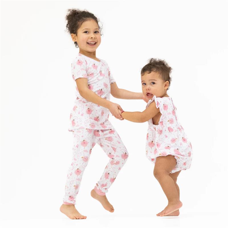 Girls playfully holding hands, wearing matching floral loungewear sets. The older girl in a short-sleeve top and pants, the younger in a sleeveless romper.