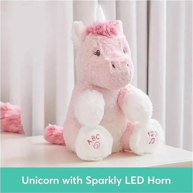 Plush pink unicorn toy with sparkly LED horn, featuring alphabet and number details on its paws.