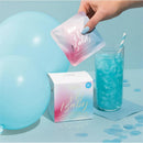 Blue Cotton Candy Drink Glitter Bombs package next to a glass and cocktail, showcasing vibrant blue colors and sparkles.
