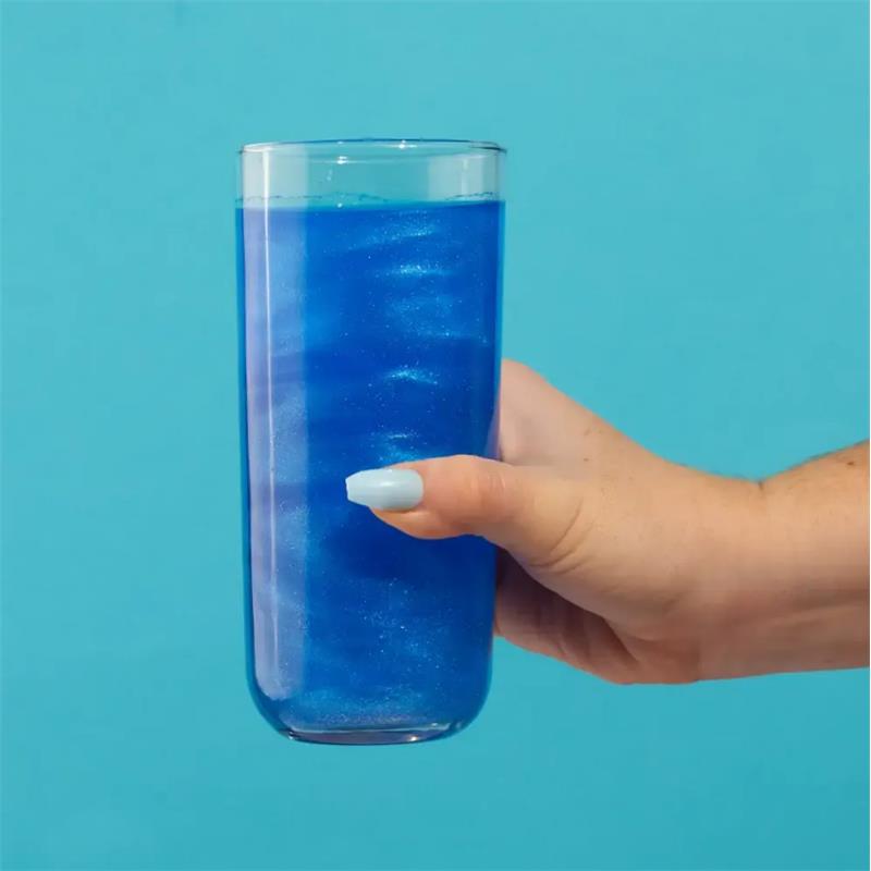 Glittering blue cotton candy drink held in a glass, featuring vibrant blue hues against a simple background.
