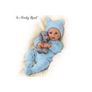 Baby boy doll in a light blue outfit holding a gray plush dog, wearing a matching bear hat.