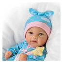 Ashton Drake Baby Doll Rylee, wearing a blue pajama and pink hat, holding a star-shaped toy, is nestled in a soft white blanket.
