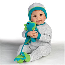 Ashton Drake Ryan And Rex Baby Boy Doll wearing a gray outfit with teal accents, holding a plush dinosaur toy.