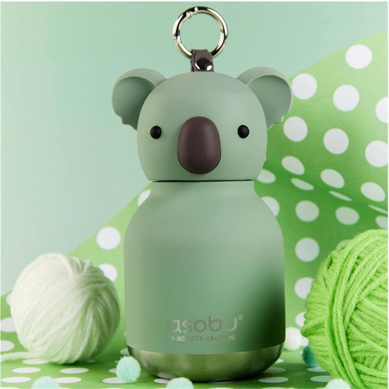 Asobu Bestie Bottle in a koala design, featuring a green body and a brown nose, surrounded by yarn and green polka dots.