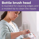 A woman uses a bottle brush with a rounded head to clean the edges and tip of a baby bottle.