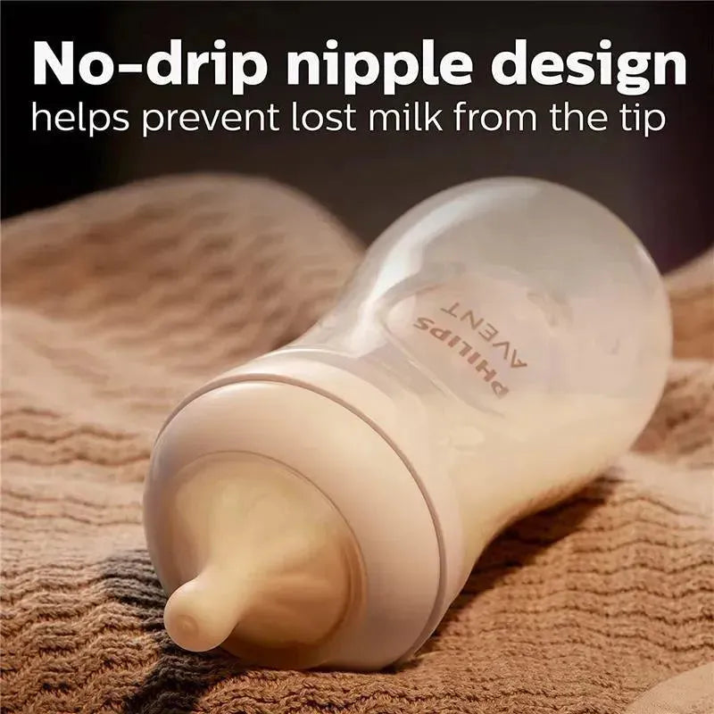 Avent Natural Baby Bottle with a no-drip nipple design, resting on a textured fabric surface.