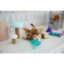 Plush monkey toy from Avent - Soothie Snuggle, with a blue pacifier and colorful wooden mushrooms on a table.
