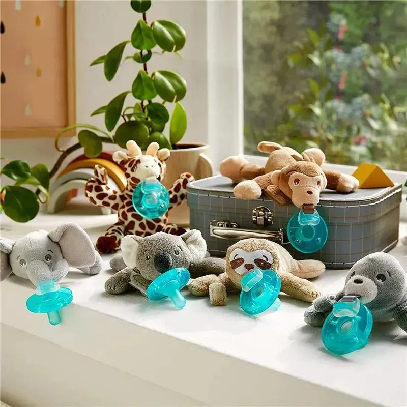 Avent Soothie Snuggle plush pacifiers featuring a sloth design, surrounded by other animal-shaped pacifiers on a table.