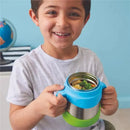 A smiling boy holds a lilac and green B.box insulated food jar filled with pasta and vegetables.