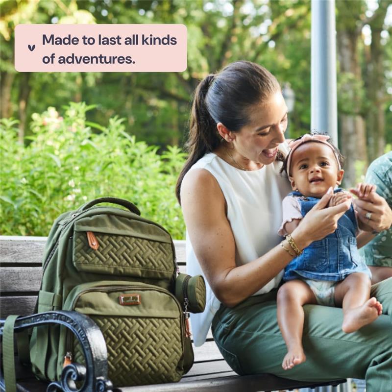Light gray BabbleRoo travel backpack with changing pad sits on a bench next to a mother and her baby, outdoors.