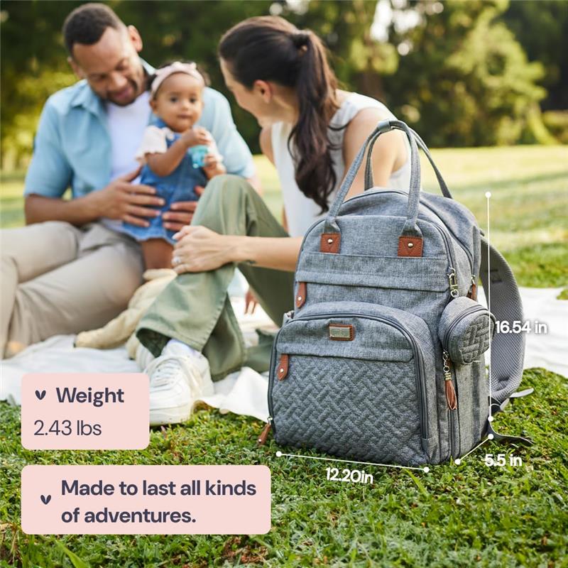 Travel essentials baby bag in brown with a changing pad sits on grass, beside a couple enjoying time with their baby.