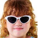 Children’s cat-eye shaped UV sunglasses in white worn by a smiling child with curly red hair.