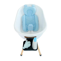 Bath support pillow in sky blue, placed in a white baby bathtub with a shelf holding a bottle and a toy dolphin.