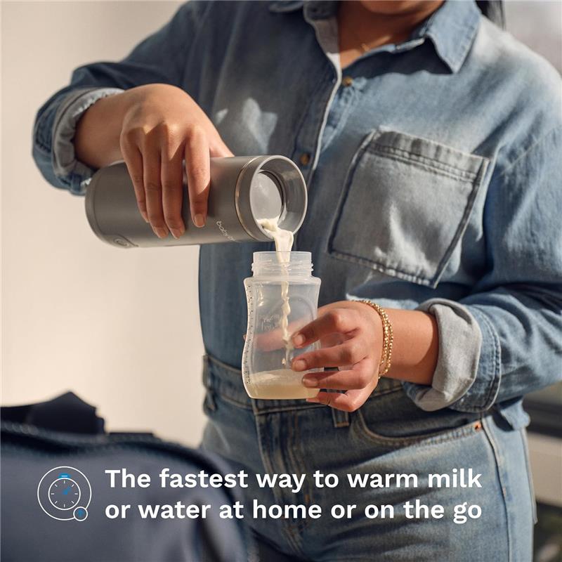 Baby Brezza Super Fast Portable Bottle Warmer in black, pouring milk from a thermal flask into a baby bottle.
