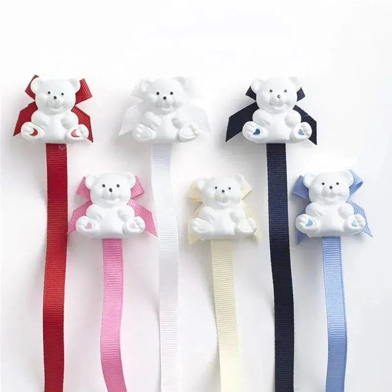 Universal pacifier holders in navy and pastel colors featuring teddy bear designs with ribbons.
