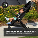 Baby Jogger City Tour 2 Travel Stroller with a smiling child seated inside, surrounded by blooming flowers, showcasing eco-friendly features.