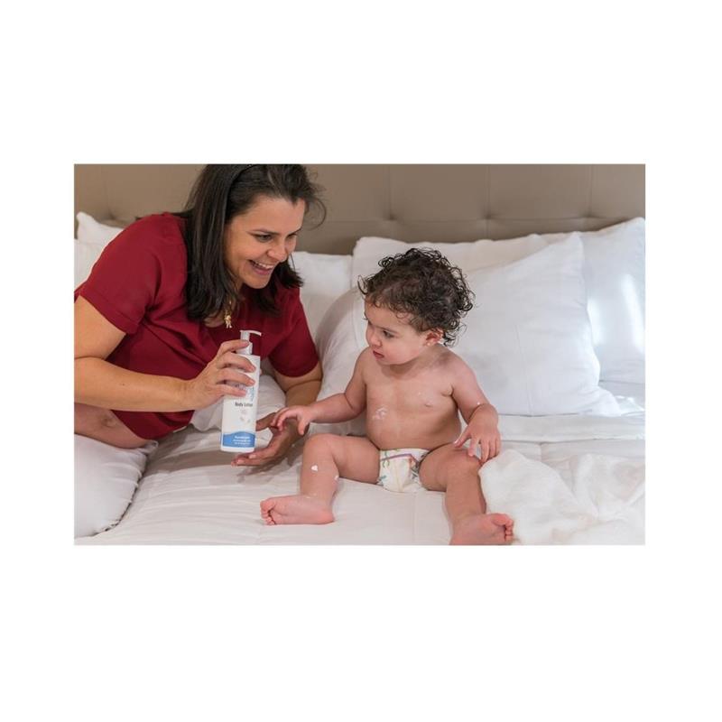 Mother applying Baby Jolie lotion to her toddler on a bed, showcasing the Baby Bath and Moisturize Set.