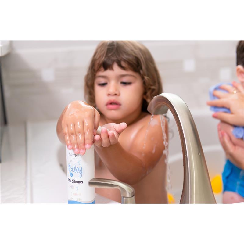 Child applying Baby Jolie conditioner at a bath, with water running from the faucet and another child in the background.