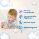 A young child inspecting a bottle of Baby Jolie Memory Baby Perfume, with labels indicating natural ingredients, dermatologist approval, alcohol-free, and hypoallergenic.