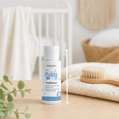 Travel size 2oz Baby Jolie conditioner with text describing benefits, placed on a wooden surface next to a brush and soft fabric.