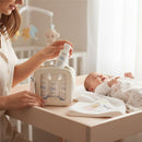 A parent holds a Baby Jolie Travel Kit, featuring bottles of hair and body wash, lotion, and conditioner, beside a smiling baby.
