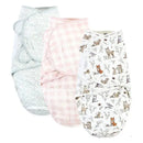 Three quilted cotton swaddle wraps in pastel colors featuring floral, gingham, and enchanted forest animal patterns.