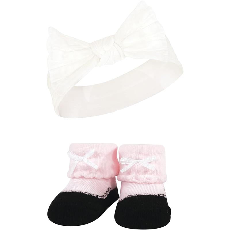 Knit headband with a large white bow and pink taupe socks with black soles and white bows.