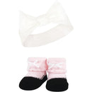 Knit headband with a large white bow and pink taupe socks with black soles and white bows.