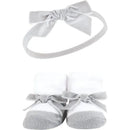 Black and silver headband with a bow above white socks adorned with gray bows in a gift set for baby girls.