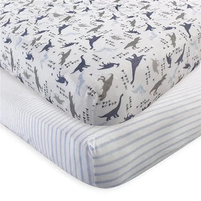 Unisex organic cotton crib sheet featuring a dinosaur print in various colors, layered over a striped sheet.