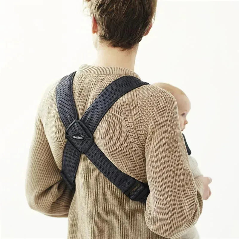Babybjorn Baby Carrier Mini in Anthracite worn by a person holding a baby, featuring a mesh design for comfort.