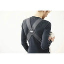 BabyBjorn Baby Carrier Mini in Dark Gray is worn by a person holding a baby; features adjustable straps and a secure design.