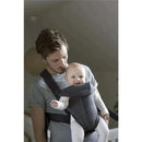 Dark gray BabyBjorn Baby Carrier Mini worn by a man, holding a smiling baby facing outward.