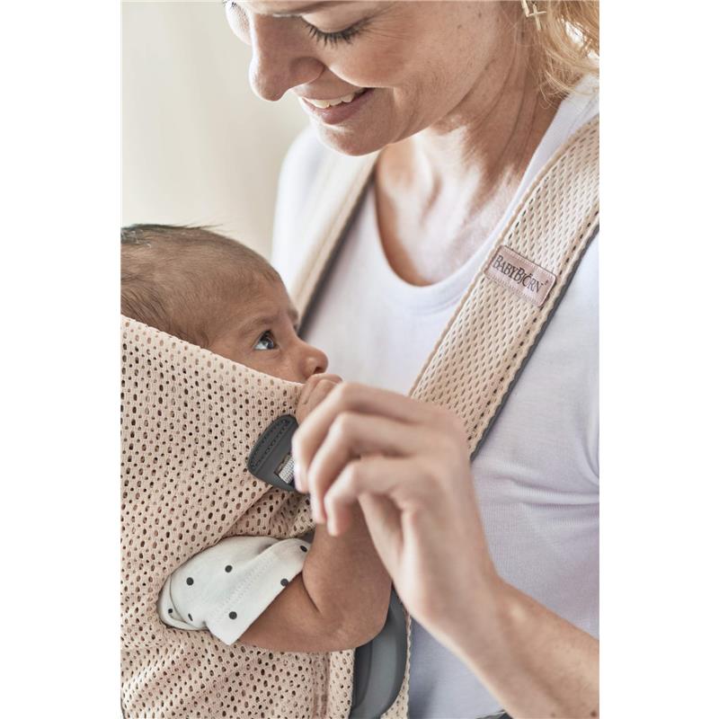 BabyBjörn Baby Carrier Mini in Pearly Pink, with a mother holding a baby securely in the mesh fabric, both smiling.