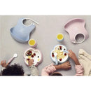 BabyBjorn baby spoon and fork set in powder blue, featuring two cute plates with food and colorful bibs on toddlers.