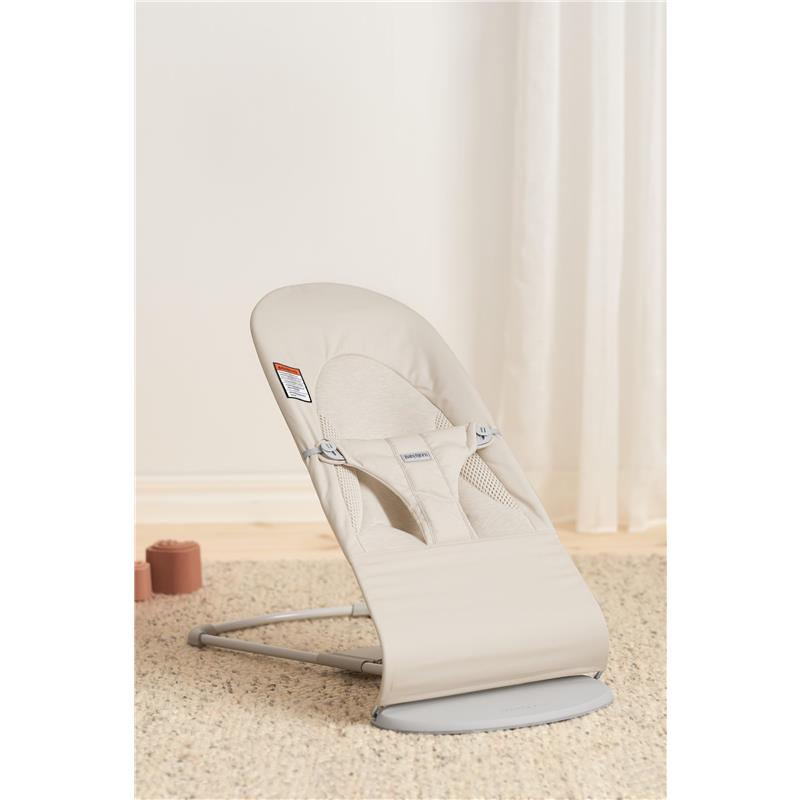 Adjustable BabyBjörn Bouncer Balance Soft in light beige, featuring a comfortable seat and safety harness, on a textured rug.