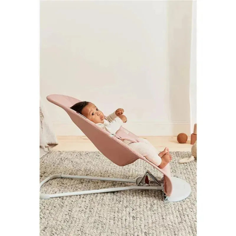 Babybjorn Bouncer Bliss in Dusty Pink with a seated baby, featuring a soft quilted design and a light wooden floor background.