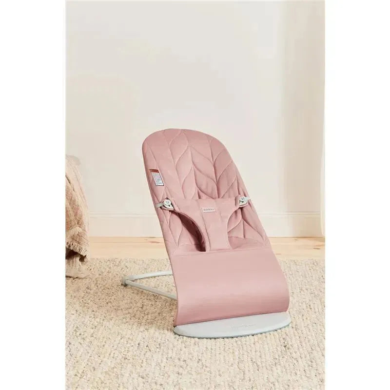 Babybjorn Bouncer Bliss in Dusty Pink, featuring a woven petal quilt design and a sturdy frame, positioned on a soft rug.