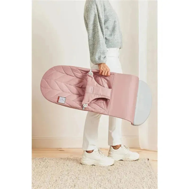 A person holding the Babybjorn Bouncer Bliss in Dusty Pink with a textured petal quilt design.