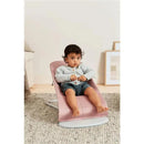 Babybjorn Bouncer Bliss in Dusty Pink, featuring a seated child wearing a gray cardigan and shorts on a soft rug.