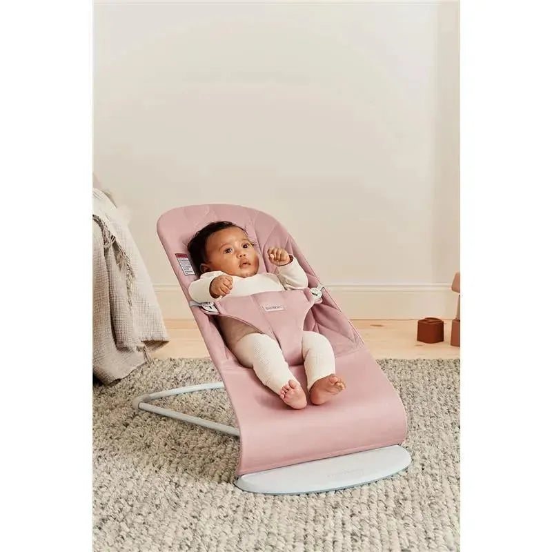 Babybjorn Bouncer Bliss in dusty pink, featuring a baby wearing a white outfit, comfortably seated and engaged.