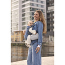 Light gray BabyBjörn Pocket Pouch attached to a baby carrier worn by a smiling mother holding her baby.