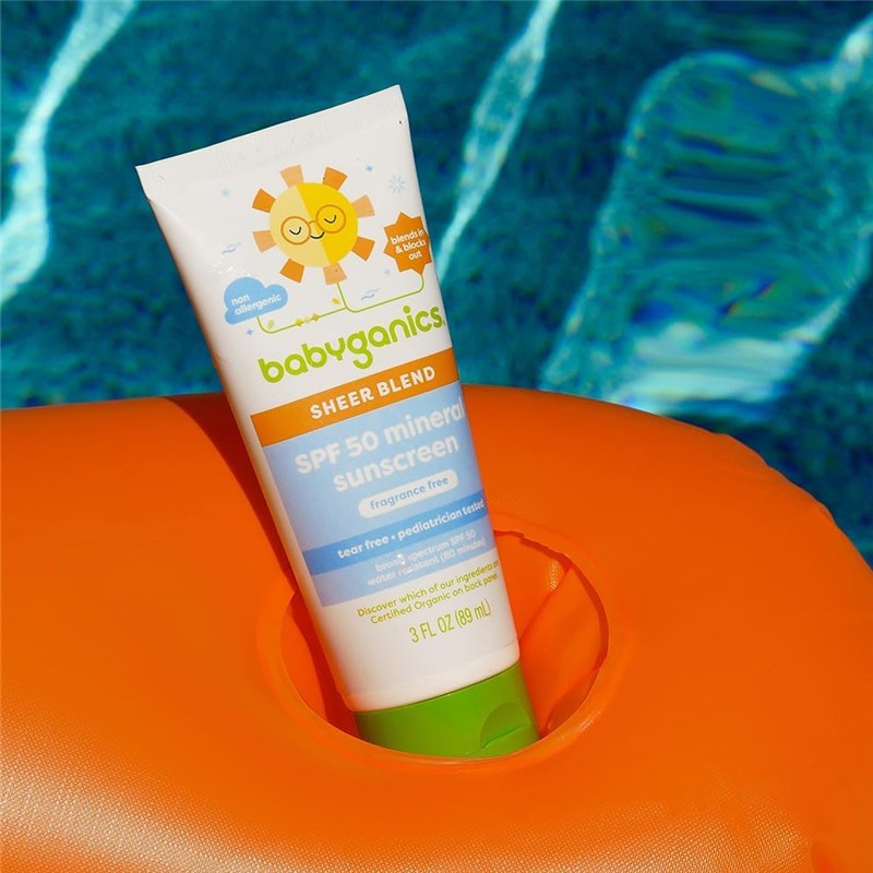 Babyganics Kids Mineral Sunscreen Lotion SPF 50 in a white tube resting on an orange float in clear water.