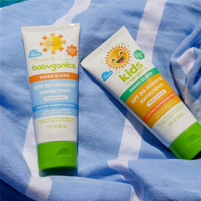 Babyganics Kids Mineral Sunscreen Lotion SPF 50, 3 fl oz tubes, featuring colorful packaging with sun designs, on a blue beach towel.