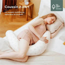 A woman in a light pink outfit sleeps peacefully, hugging a white, heart-patterned 2-in-1 pregnancy and nursing pillow.