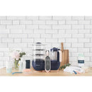 Babymoov Duo Meal Station XL, a 6-in-1 food processor with steamer, multi-speed blender, and control panel, on a wooden countertop.